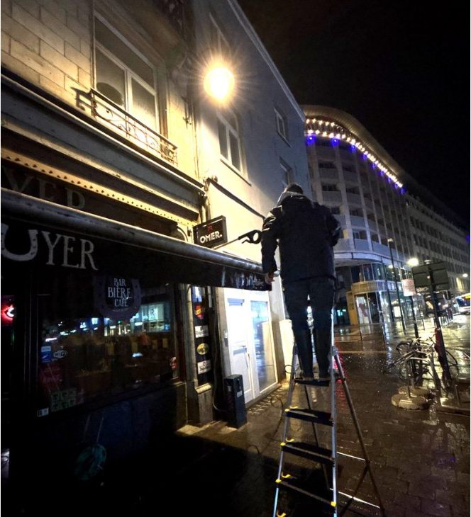 Nettoyage de bâche de façade de bar en soirée